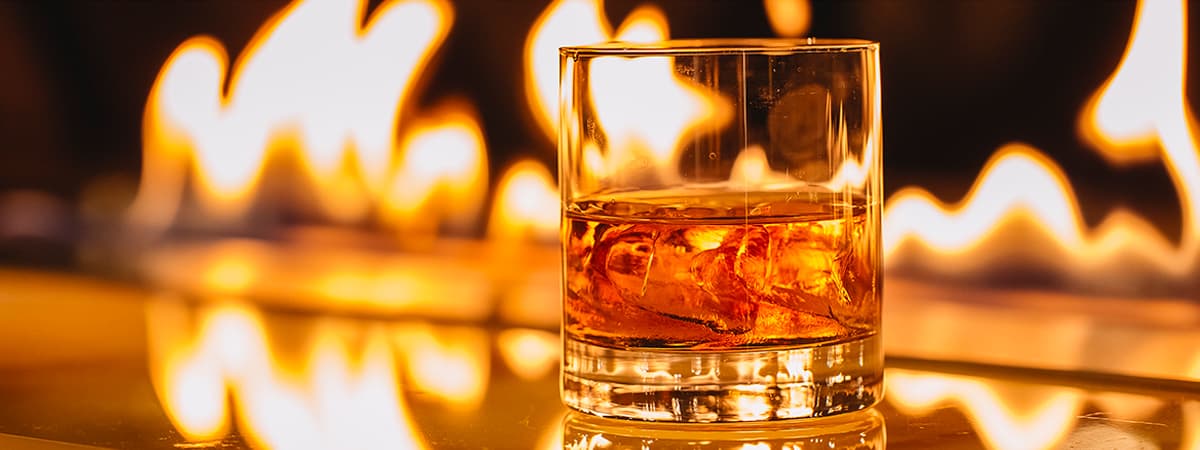 side-view-glass-whiskey-with-ice-background-burning-flame-header